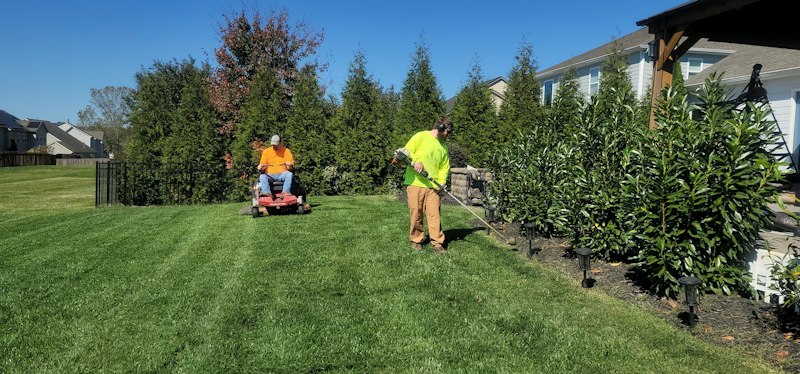 A landscaping crew mowing and trimming a lawn