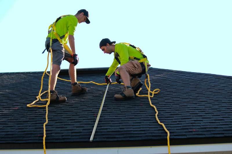 Two roofers working on a shingle roof